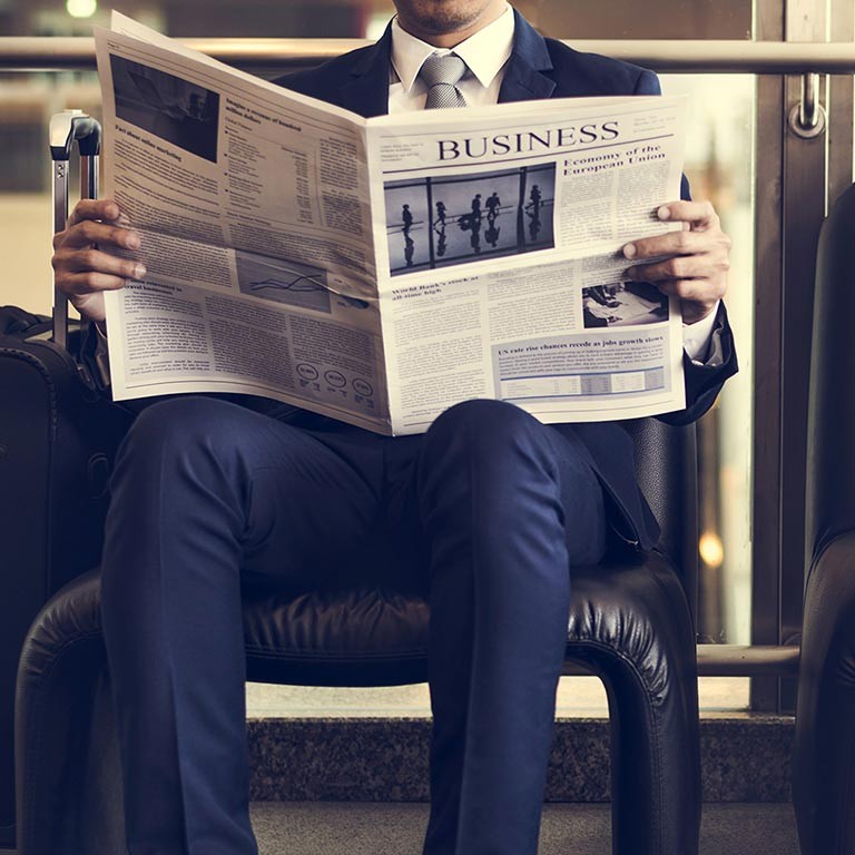 Forretningsmand sidder og læser nyheder i en avis